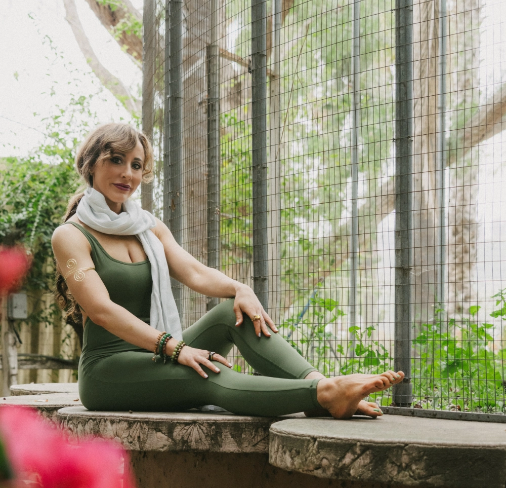 Woman in yoga pose, wearing green outfit.