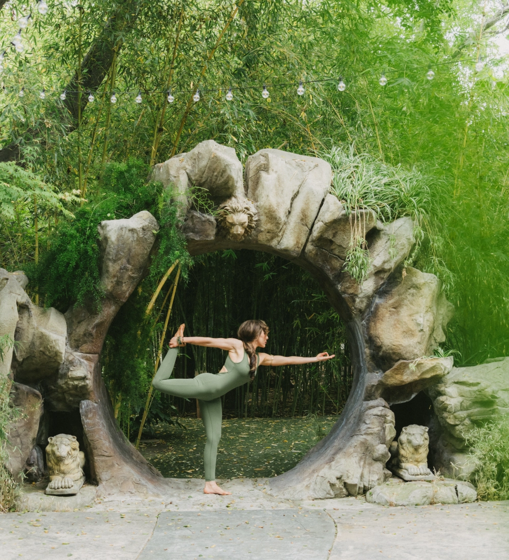 Person doing yoga pose in nature archway.